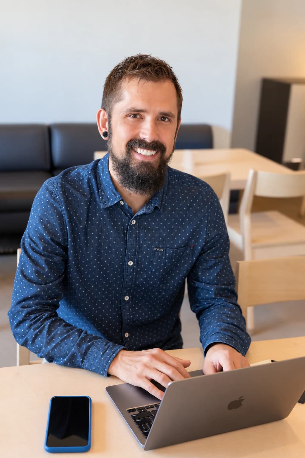 Alexander Gartley smiling while seated at a table with his laptop